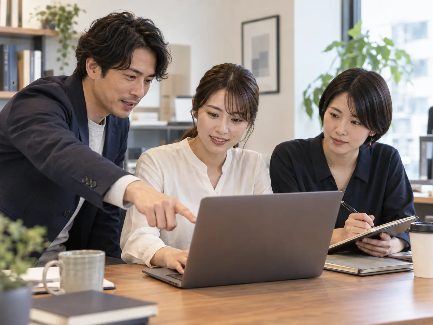 少人数でパソコンを囲み、新しい作業手順を試すイメージ